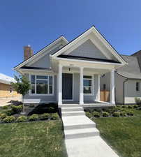View of front of home with a chimney, a front lawn, and covered porch