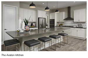 Kitchen featuring quartz countertops, wall chimney exhaust hood, and a kitchen bar