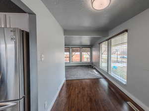 Empty room with dark wood-style floors, a textured ceiling, and baseboards