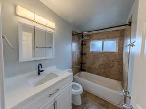 Bathroom with toilet, vanity, a textured ceiling, and shower / bathing tub combination