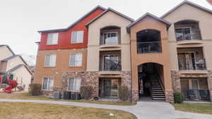 View of building exterior featuring stairs and central AC