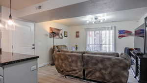 Living room featuring visible vents, a textured ceiling, and light wood finished floors