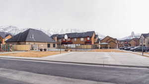 View of front of house featuring a residential view, a mountain view, fence, and playground community