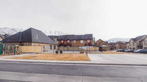 View of front facade with a residential view, playground community, a mountain view, and fence