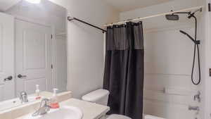 Bathroom featuring toilet, shower / bath combination with curtain, and vanity