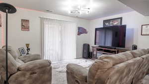 Carpeted living room with a chandelier, plenty of natural light, and visible vents