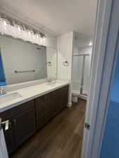 Bathroom featuring wood-type flooring, a shower with shower door, vanity, a textured ceiling, and toilet