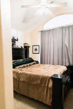 Carpeted bedroom featuring vaulted ceiling and ceiling fan