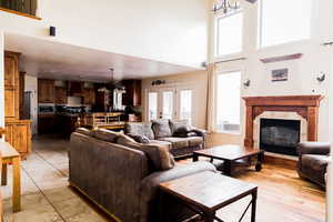 Living room featuring french doors, light tile patterned flooring, a stone fireplace, and a towering ceiling