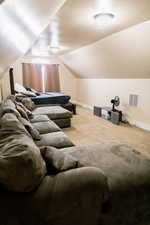 Home theater room featuring vaulted ceiling, carpet flooring, visible vents, and baseboards