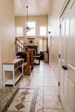 Interior space featuring light tile patterned floors, a high ceiling, a ceiling fan, baseboards, and stairs