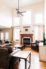 Living area with light wood finished floors, a glass covered fireplace, and a high ceiling