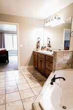 Full bathroom featuring baseboards, vanity, a bath, and tile patterned floors