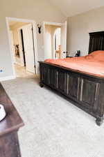 Bedroom with light carpet, light tile patterned floors, baseboards, and vaulted ceiling