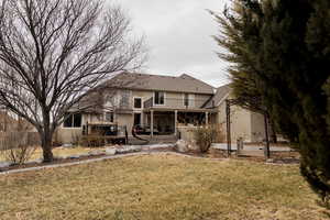 Back of house with a lawn, a balcony, and stucco siding