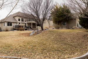 Back of house featuring a lawn, a wooden deck, and stucco siding