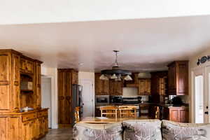 Kitchen featuring pendant lighting, light tile patterned floors, stainless steel appliances, dark countertops, and a sink