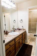 Bathroom with toilet, bath / shower combo with glass door, vanity, and tile patterned floors