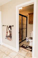 Full bath featuring a shower stall, tile patterned flooring, toilet, and baseboards