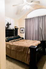 Bedroom with vaulted ceiling, a ceiling fan, and light colored carpet