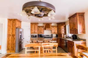 Kitchen with brown cabinetry, custom range hood, stainless steel appliances, and a sink