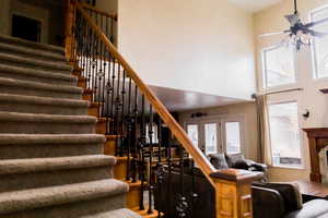 Staircase featuring french doors, ceiling fan, and a towering ceiling