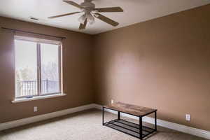 Spare room with a ceiling fan, carpet flooring, visible vents, and baseboards