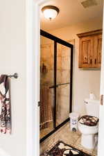 Full bathroom featuring toilet, a stall shower, visible vents, and tile patterned floors