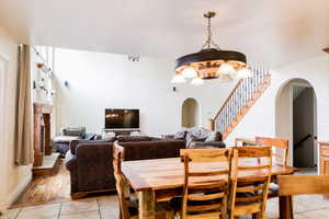 Dining area with arched walkways, light tile patterned flooring, and stairway