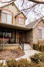 View of front of property featuring a porch, stone siding, and a shingled roof