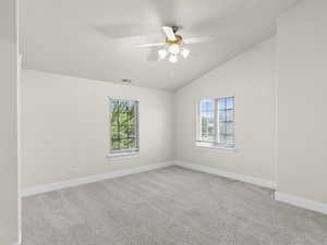 Unfurnished room with ceiling fan, lofted ceiling, light carpet, visible vents, and baseboards