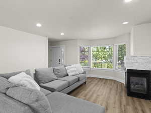 Living room featuring light wood-type flooring, baseboards, a glass covered fireplace, and recessed lighting