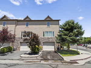 View of front of property with stone siding, driveway, and stucco siding