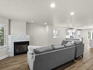 Living area featuring baseboards, a stone fireplace, recessed lighting, and light wood-style floors