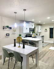 Dining room featuring recessed lighting, baseboards, light wood-style flooring, and a textured ceiling