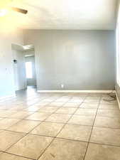 Unfurnished room with a ceiling fan, baseboards, and light tile patterned floors