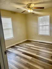 Empty room featuring visible vents, a textured ceiling, baseboards, and wood finished floors