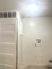 Washroom with a textured ceiling, laundry area, washer hookup, and electric dryer hookup