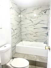 Full bathroom featuring a textured ceiling,  shower combination, and toilet