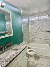 Bathroom featuring shower / washtub combination, a textured ceiling, toilet, and vanity