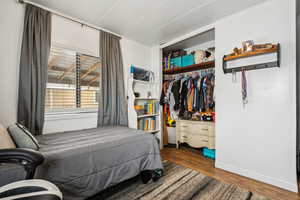 Bedroom with dark wood-type flooring and a closet