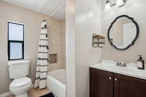 Full bath featuring toilet, shower / bathtub combination with curtain, baseboards, and vanity
