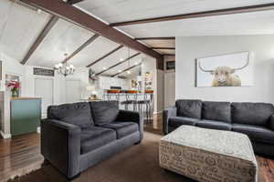 Living area featuring lofted ceiling with beams, dark wood-style floors, baseboards, and a notable chandelier