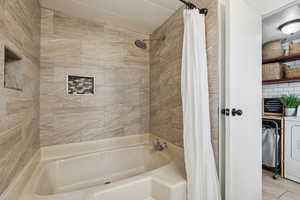 Bathroom with washer / clothes dryer and shower / tub combo