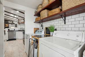 Washroom featuring laundry area, washing machine and dryer, a chandelier, and a sink