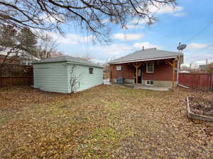 Back of house featuring cooling unit, a fenced backyard, an outdoor structure, and a patio