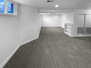 Below grade area with recessed lighting, dark carpet, visible vents, and baseboards