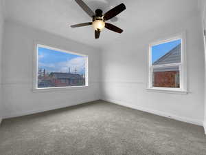 Spare room featuring carpet floors, plenty of natural light, baseboards, and a ceiling fan