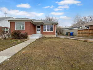 Bungalow featuring brick siding, a front lawn, and fence