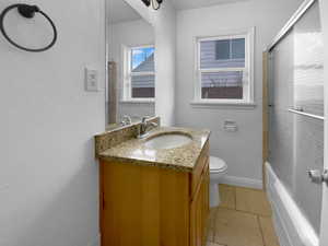 Bathroom featuring toilet, baseboards, combined bath / shower with glass door, and vanity